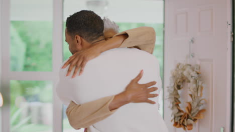 Adult-Son-Greeting-Senior-Mother-As-She-Arrives-To-Celebrate-Christmas-At-Home