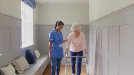 Portrait-Of-Senior-Woman-At-Home-Using-Walking-Frame-Being-Helped-By-Female-Care-Worker-In-Uniform