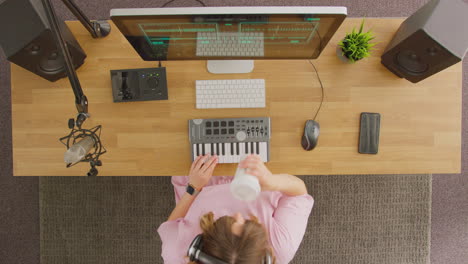 Overhead-View-Of-Female-Musician-At-Workstation-With-Keyboard-And-Microphone-In-Studio
