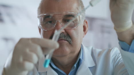 Technician-carefully-drips-the-solution-from-the-pipette-into-glass-tubes-for-DNA-analysis.-Doctor-Drips-Blue-Solution-Into-Glass-Tube-Coronavirus-Pandemic-Hands-Closeup.-High-quality-4k-footage