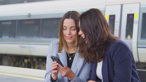 Mujeres-Empresarias-Que-Viajan-Al-Trabajo-Esperando-El-Tren-En-El-Andén-De-La-Estación-Tomando-Selfie-En-El-Teléfono-Móvil