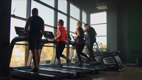 Young-athletic-men-and-women-exercising-and-running-on-treadmill-in-sport-gym.