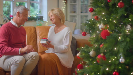 Liebendes-älteres-Paar-Feiert-Zu-Hause-Mit-Champagner-Rund-Um-Den-Weihnachtsbaum