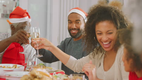 Couple-Wearing-Santa-Hats-Enjoying-Eating-Christmas-Meal-At-Home-Together