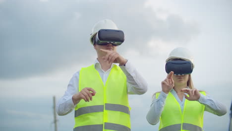 A-man-and-a-woman-engineer-in-VR-glasses-control-the-power-distribution-of-electric-networks-and-the-delivery-of-electricity-against-the-background-of-electric-towers-with-high-voltage-cables