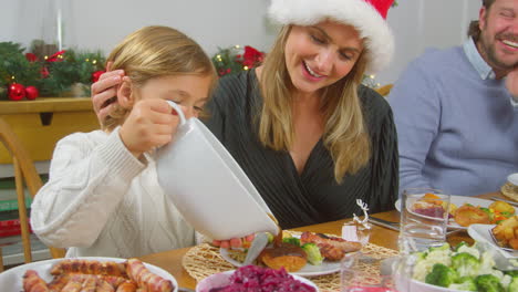 Sohn-Gießt-Soße-Auf-Sein-Essen,-Während-Die-Familie-Weihnachtsessen-Isst