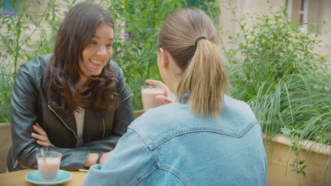 Happy-Same-Sex-Female-Couple-Meeting-And-Sitting-Outdoors-At-Coffee-Shop-Together