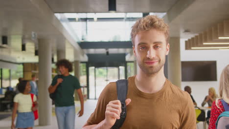Portrait-Of-Male-Student-In-Busy-University-Or-College-Building