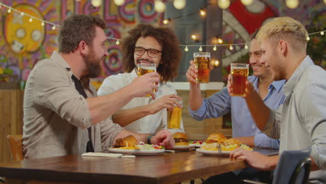 Multi-Cultural-Male-Friends-Sitting-At-Table-Eating-Meal-In-Restaurant-Enjoying-Girls-Night-Out