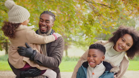 Portrait-of-smiling-family-with-parents-with-children-on-walk-through-autumn-countryside-together-looking-at-camera---shot-in-slow-motion