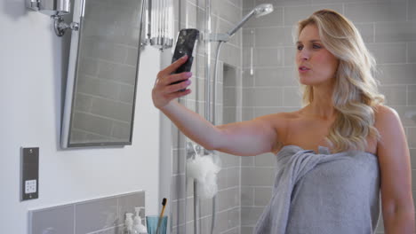 Mujer-Madura-Preparándose-En-El-Baño-De-Casa-Posando-Para-Selfie-En-Teléfono-Móvil