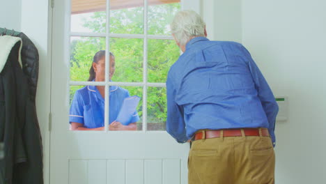 Älterer-Mann-Zu-Hause-Mit-Gehstock-Und-Begrüßung-Einer-Krankenschwester-Oder-Einer-Pflegekraft-In-Uniform-An-Der-Tür
