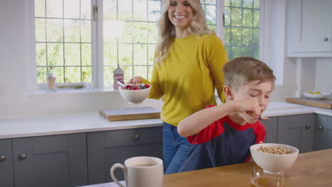 Mother-And-Son-At-Home-Eating-Breakfast-Cereal-At-Kitchen-Counter-Together