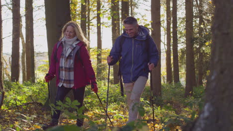Mature-couple-walking-through-fall-or-winter-countryside-using-hiking-poles---shot-in-slow-motion