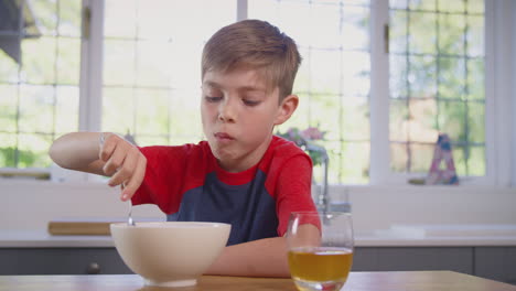 Boy-At-Home-Eating-Bowl-Of-Breakfast-Cereal-At-Kitchen-Counter
