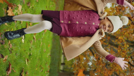 Vertical-video-of-young-girl-having-fun-throwing-autumn-leaves-into-the-air-on-walk-in-countryside---shot-in-slow-motion