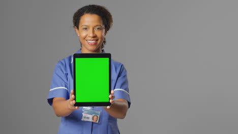 Porträt-Einer-Lächelnden-Krankenschwester-In-Uniform,-Die-Ein-Digitales-Tablet-Mit-Leerem-Grünen-Bildschirm-Hält