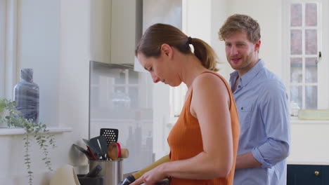 Paar-Mit-Frau-Mit-Armprothese-In-Der-Küche,-Die-Gemeinsam-Essen-Zubereitet