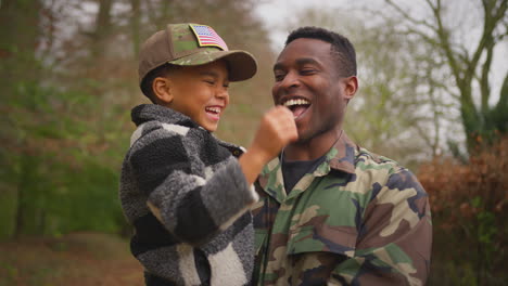 Close-Up-Of-American-Soldier-Returning-Home-To-Family-On-Leave-Carrying-Son-Wearing-Army-Cap