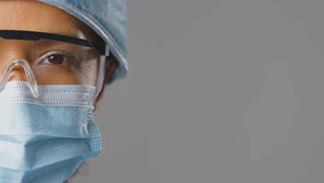 Close-Up-Studio-Portrait-Of-Female-Surgeon-With-Safety-Glasses-Wearing-Scrubs-And-Face-Mask