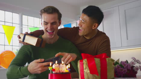 Same-Sex-Male-Couple-Celebrating-30th-Birthday-At-Home-With--Man-Taking-Photo-Of-Cake-On-Phone