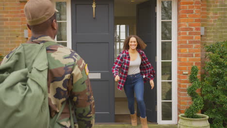 American-Soldier-In-Uniform-Returns-Home-To-Family-On-Leave-Hugging-Wife-And-Children-Outside-House