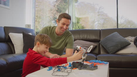Father-and-son-wearing-pyjamas-building-robotic-arm-from-plastic-kit-at-home-for-science-project---shot-in-slow-motion