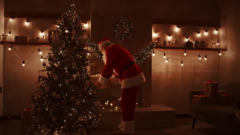 Santa-Claus-brings-gifts-under-the-Christmas-tree-for-children.-Give-gifts-to-children-on-Christmas-night.-Santa-puts-a-gift-under-the-Christmas-tree.-High-quality-4k-footage