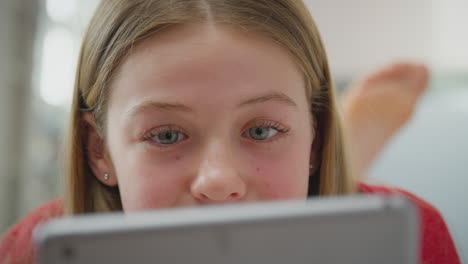 Nahaufnahme-Eines-Teenager-Mädchens-Mit-Kieferorthopädischen-Zahnspangen,-Das-Zu-Hause-Auf-Dem-Bett-Liegt-Und-Auf-Den-Bildschirm-Eines-Digitalen-Tablets-Schaut-–-Aufgenommen-In-Zeitlupe
