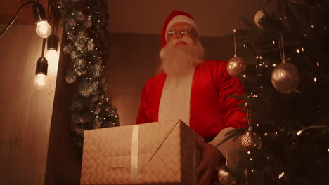 Der-Weihnachtsmann-Bückt-Sich-Und-Stellt-Eine-Große,-Schöne-Schachtel-Mit-Einem-Geschenk-Für-Ein-Braves-Kind-Unter-Den-Weihnachtsbaum.-Hochwertiges-4K-Filmmaterial