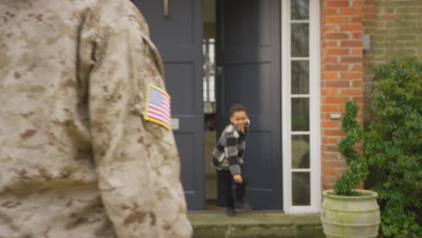 American-Female-Soldier-Returns-Home-To-Family-On-Leave-Hugging-Husband-And-Children-Outside-House