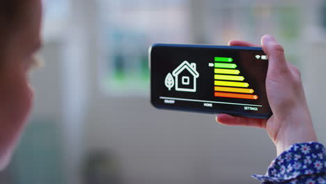 Close-up-of-woman-with-app-on-mobile-phone-to-measure-household-energy-efficiency-at-home---shot-in-slow-motion