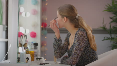 Teenage-girl-looking-in-mirror-in-bedroom-at-home-putting-on-eye-make-up---shot-in-slow-motion