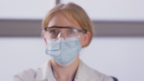 Portrait-Of-Female-Lab-Research-Worker-Wearing-PPE-Holding-Test-Tube-Labelled-Vaccine