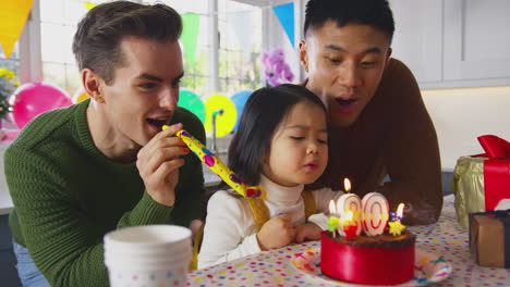 Family-With-Two-Dads-And-Daughter-Celebrate-Parents-30th-Birthday-At-Home-With-Cake-And-Party-Blower