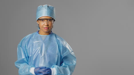 Portrait-Of-Serious-Female-Surgeon-Wearing-Safety-Glasses-Against-Grey-Background