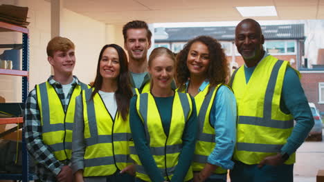 Portrait-Of-Multi-Cultural-Team-Wearing-Hi-Vis-Safety-Clothing-Working-In-Modern-Warehouse