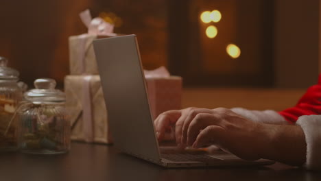 Die-Hände-Des-Weihnachtsmanns-Tippen-Auf-Einer-Laptoptastatur.-Der-Weihnachtsmann-Verteilt-Geschenke-Für-Brave-Kinder-Zu-Weihnachten-Und-Neujahr.-Hochwertiges-4K-Filmmaterial