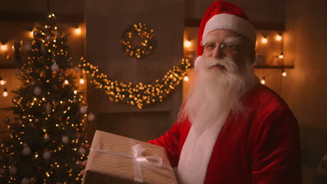 Der-Weihnachtsmann-Hält-In-Seinen-Händen-Eine-Große-Schöne-Schachtel-Mit-Einem-Geschenk-Für-Ein-Gehorsames-Kind-Für-Frohe-Weihnachten.-Schaut-In-Die-Kamera-Und-Lächelt.-Hochwertiges-4K-Filmmaterial