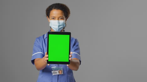 Porträt-Einer-Krankenschwester-In-Uniform-Und-Gesichtsmaske-Mit-Digitalem-Tablet-Und-Leerem-Grünen-Bildschirm