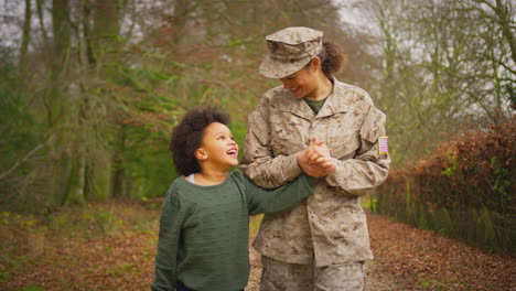 Amerikanische-Soldatin-Kehrt-Auf-Urlaub-Nach-Hause-Zur-Familie-Zurück-Und-Geht-Mit-Ihrer-Tochter-Händchen-Haltend-Spazieren