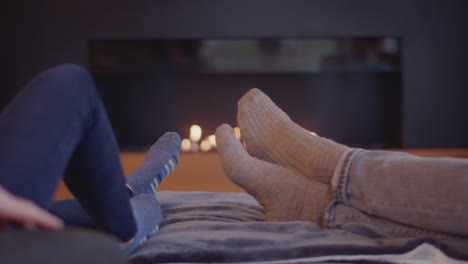 Close-Up-Of-Couple-Relaxing-And-Warming-Feet-By-Fire-At-Home