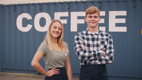 Portrait-Of-Male-And-Female-Interns-At-Freight-Haulage-Business-Standing-By-Shipping-Container
