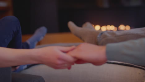 Nahaufnahme-Eines-Romantischen-Paares,-Das-Sich-Zu-Hause-Beim-Händchenhalten-Und-Füßewärmen-Am-Feuer-Entspannt