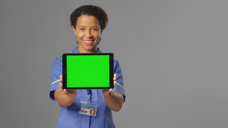 Retrato-De-Una-Enfermera-Sonriente-Con-Uniforme-Sosteniendo-Una-Tableta-Digital-Con-Pantalla-Verde-En-Blanco