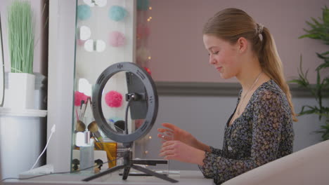 Teenage-girl-in-bedroom-recording-online-make-up-tutorial-on-mobile-phone---shot-in-slow-motion