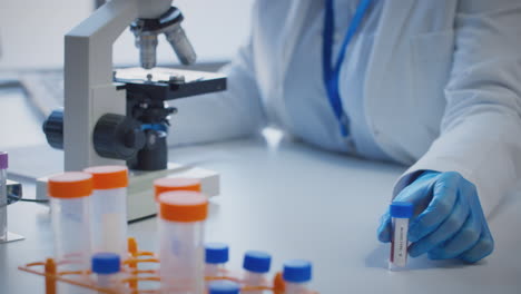 Close-Up-Of-Lab-Worker-Conducting-Research-Using-Microscope-Holding-Blood-Sample-Labelled-Type-B