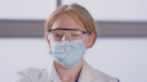 Portrait-Of-Female-Lab-Research-Worker-Wearing-PPE-Holding-Test-Tube-Labelled-Omicron
