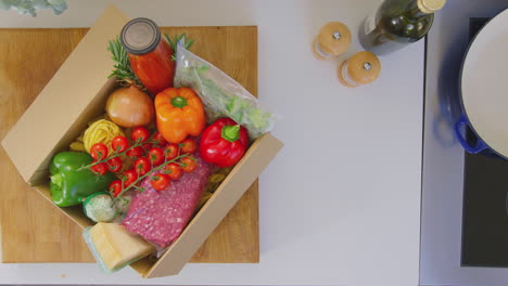 View-from-above-of-woman-putting-box-of-delivered-fresh-ingredients-on-kitchen-counter---shot-in-slow-motion