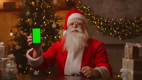 Santa-points-his-finger-at-the-green-screen-mobile-phone-screen.-Christmas-sale.-Elderly-Santa-Claus-shows-a-screen-with-a-chromakey.-High-quality-4k-footage